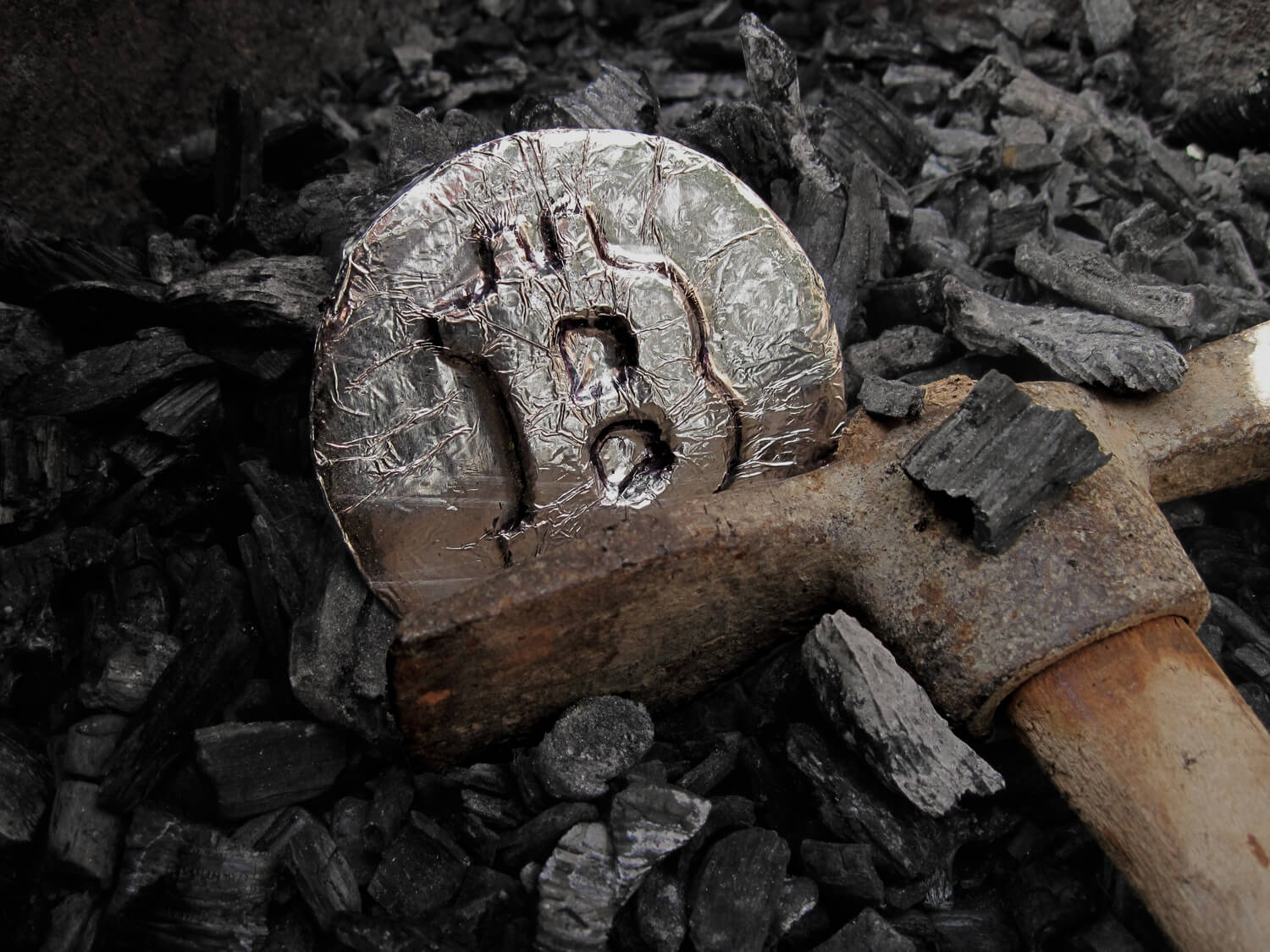 Burnt bitcoin with a hammer next to it