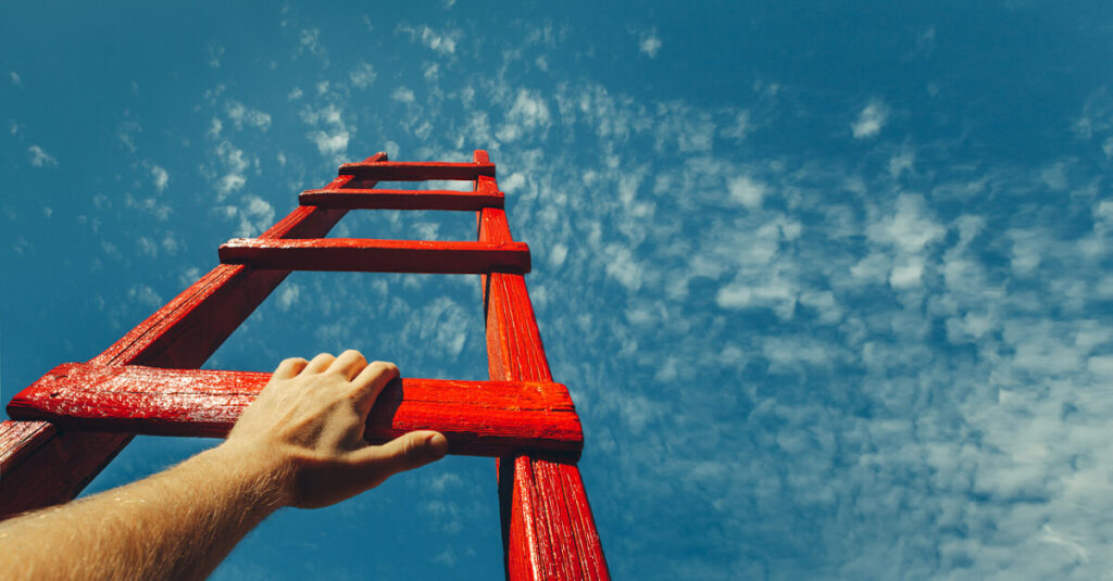 Man holding on to a red ladder