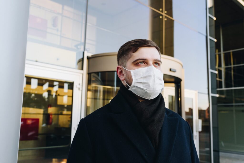 A young man wearing a face mask while leaving a building
