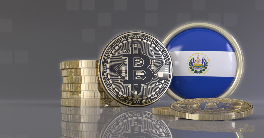 Bitcoin coin standing upright with El Salvador flag next to it