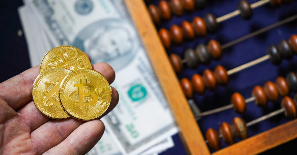bitcoins in hand above dollars and abacus