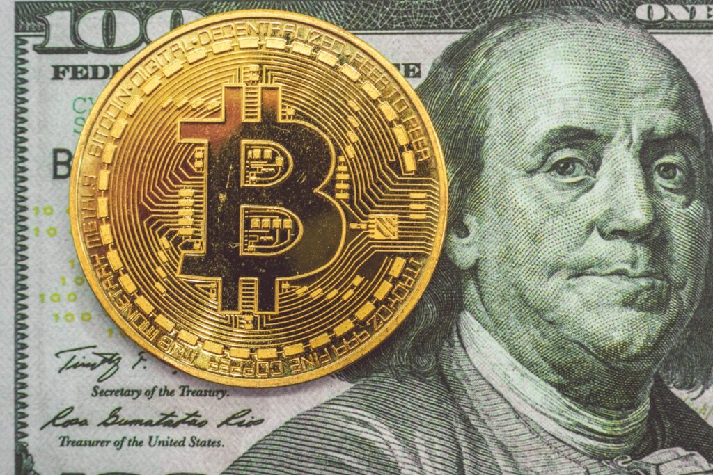 Gold Bitcoin with a 100 dollar bill background