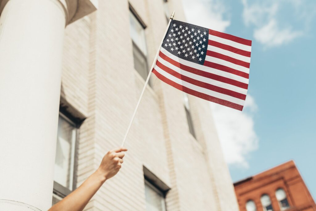 A man waving a US flag from a building