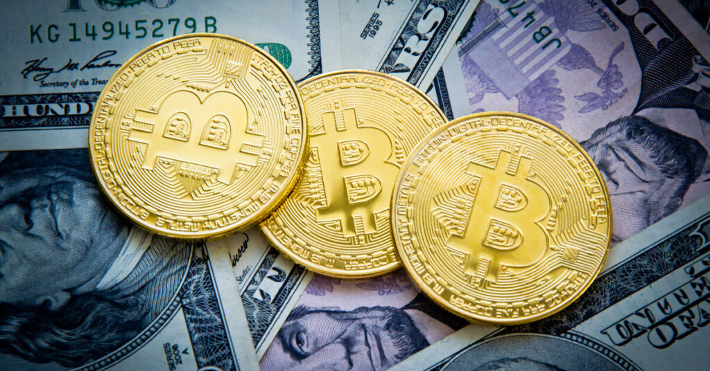 3 Bitcoin coins on US dollar notes