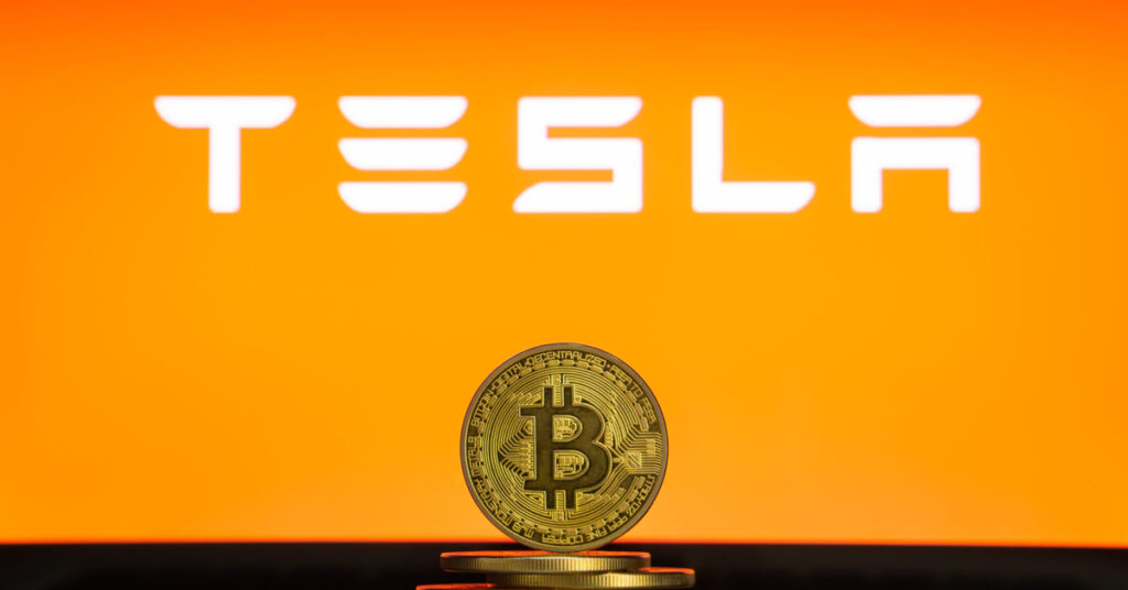 Gold Bitcoin in front of a Tesla logo