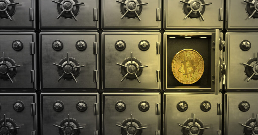Several vaults lined up with one vault uncovered showing a Bitcoin coin