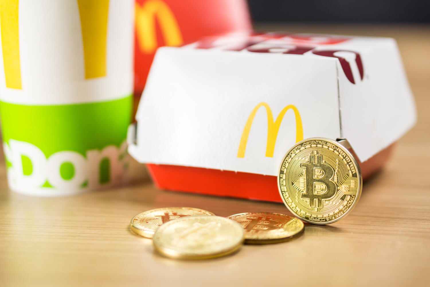 Golden Bitcoin coin propped up against a McDonalds meal