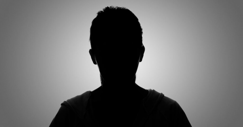 The silhouette of an anonymous person in front of a light background.