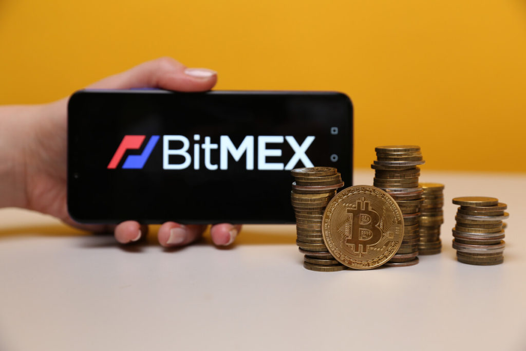 Logotipo de BitMEX en un teléfono móvil junto a monedas bitcoin 