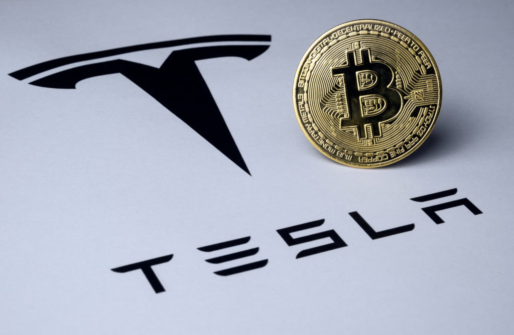 tesla logo with Bitcoin coin next to it