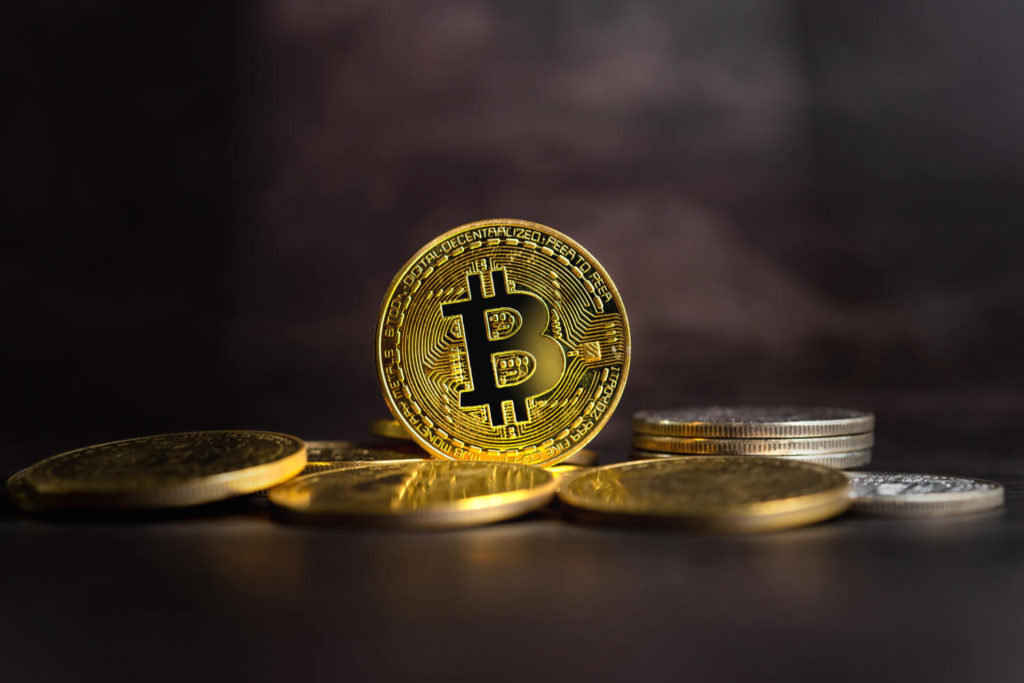 Physical Bitcoin coins spread across a dark surface.