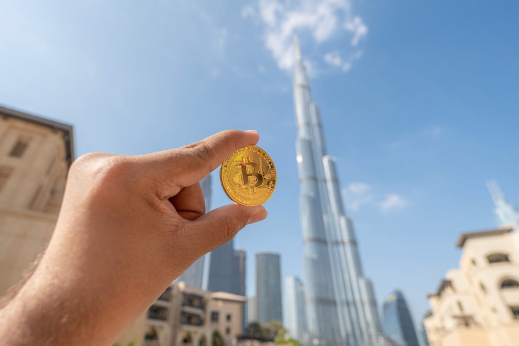 Golden Bitcoin held up in front of the Burj Khalifa in Dubai, UAE