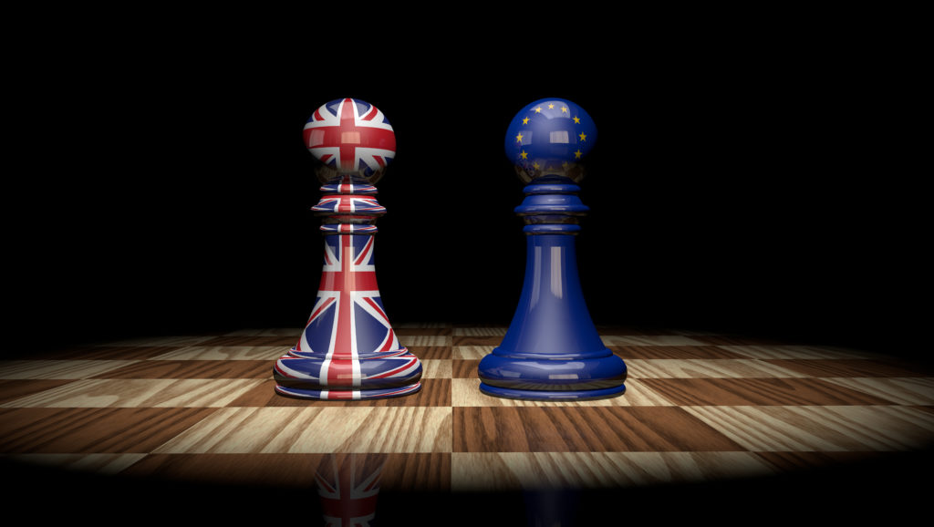 2 chess pawns, one with EU flag, other with UK flag on a chess board