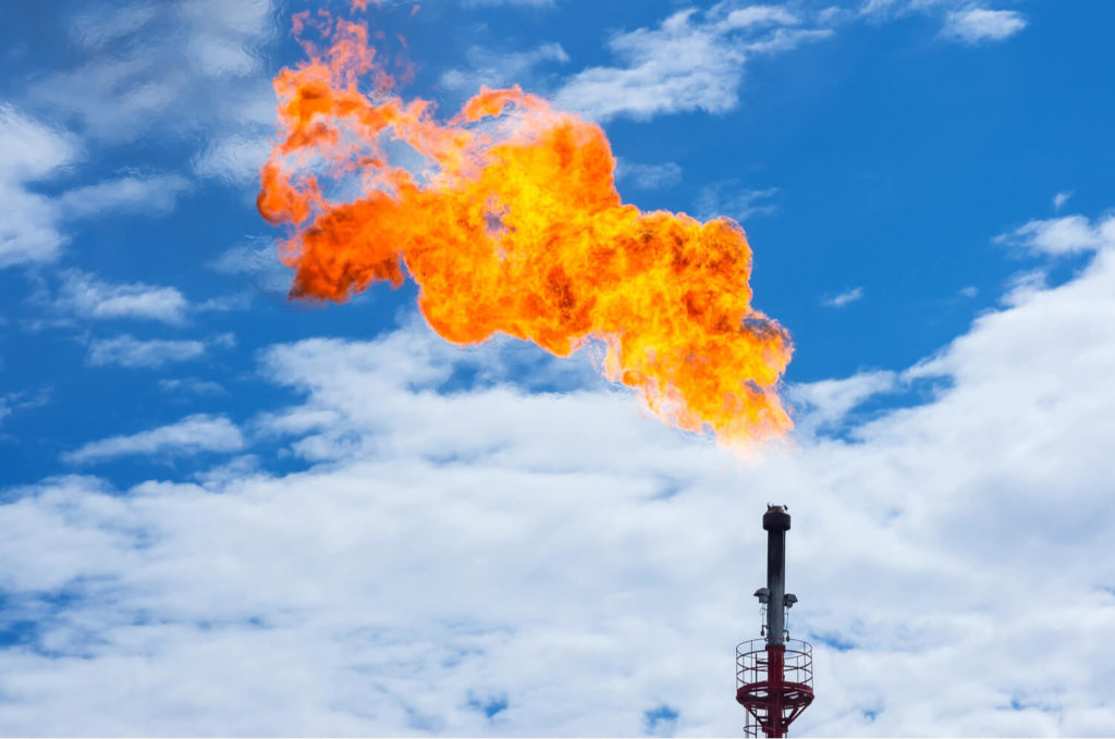 A gas flare burning with bright blue sky in the background