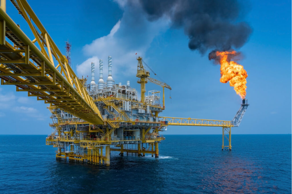 oil rig in ocean with burning gas and smoke flumes