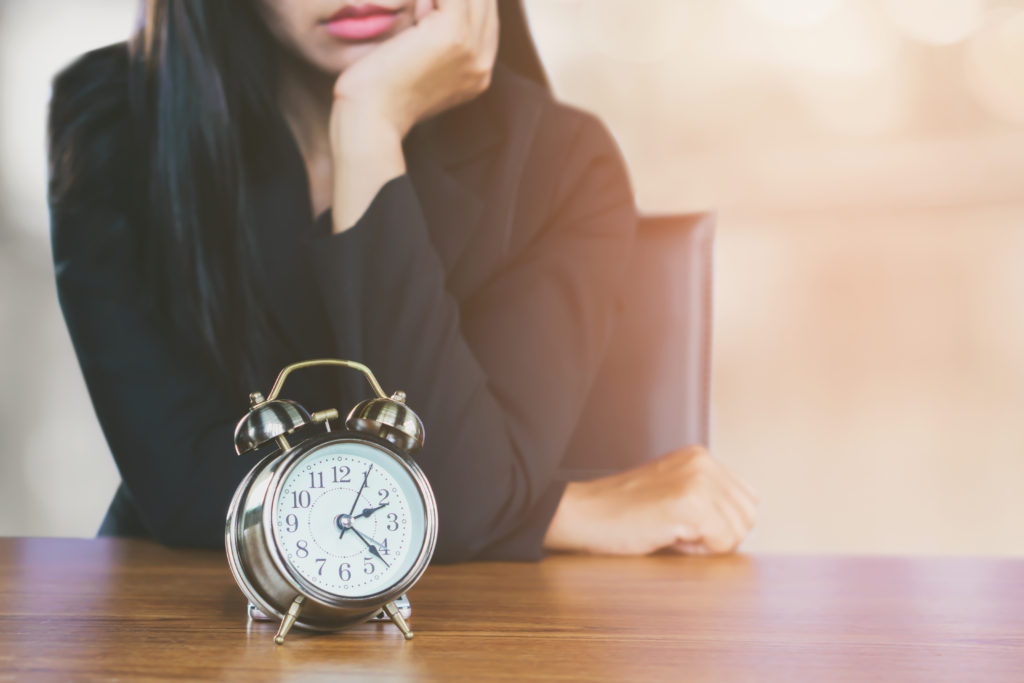 a woman waiting by the clock set on a table