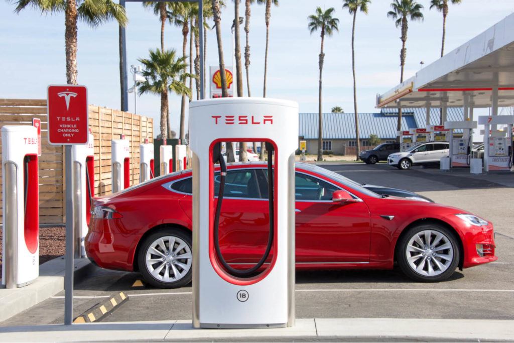 a red Tesla next to a charging station