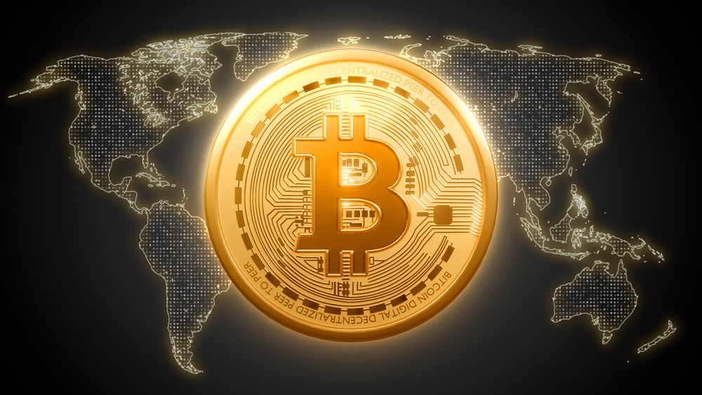 A bitcoin physical coin displayed above an international map