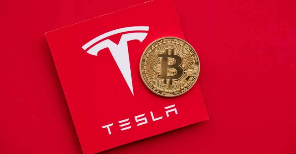 Image of the Tesla logo with a golden Bitcoin sitting on top of it