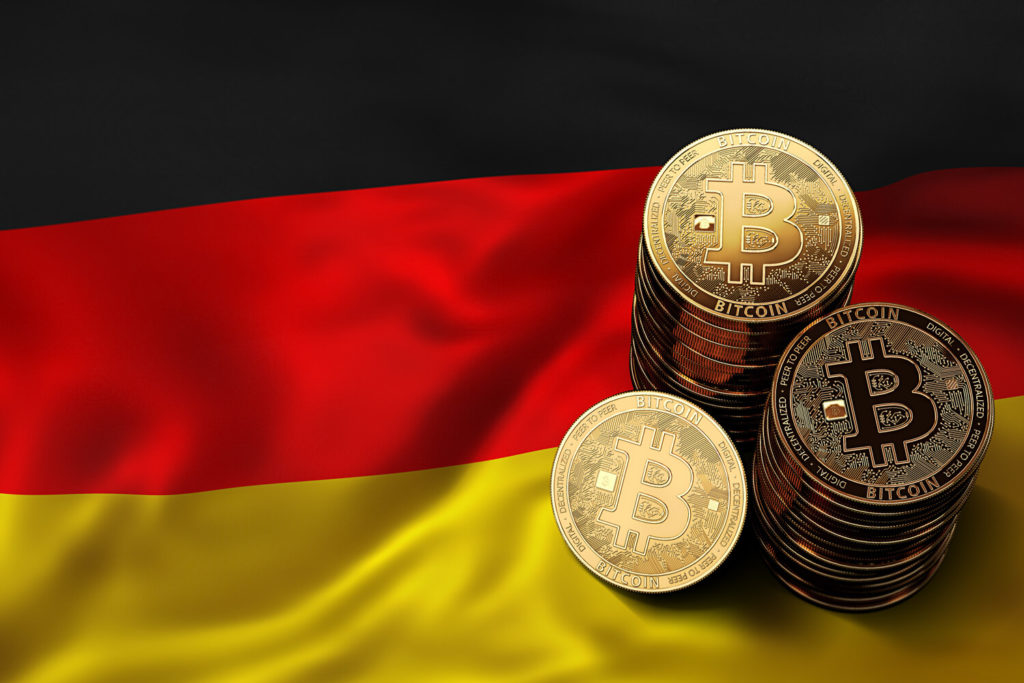 Golden bitcoins stacked on top of each other. Stacks of coins are situated on top of German flag.