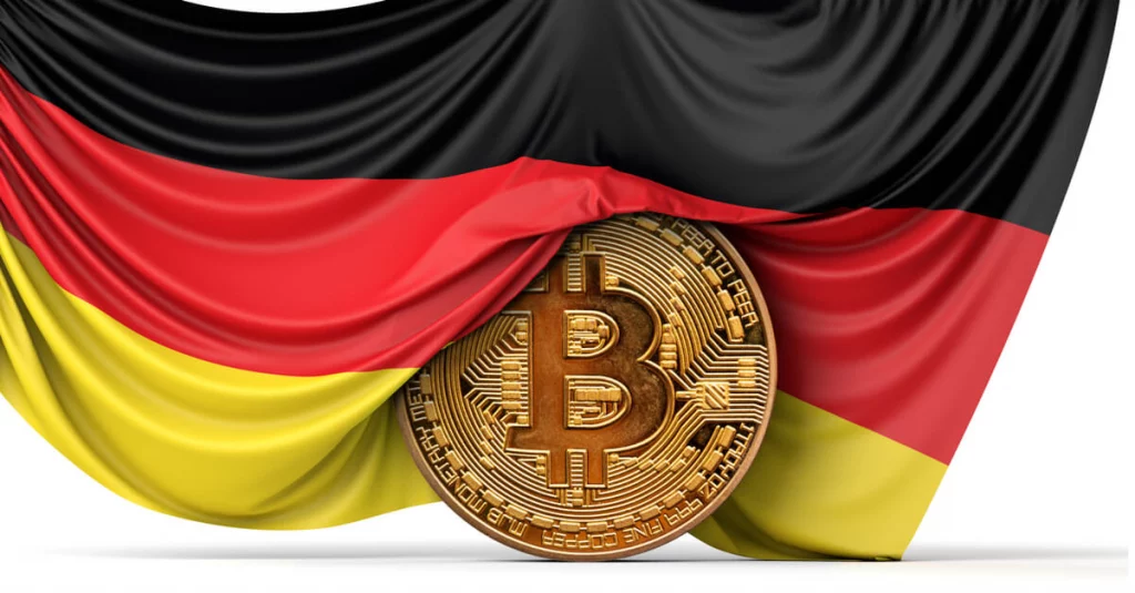 Golden Bitcoin coin standing upright, draped in the flag of Germany