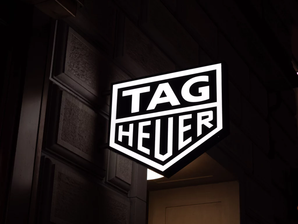 An image of the TAG Heuer logo light up at night outside a store
