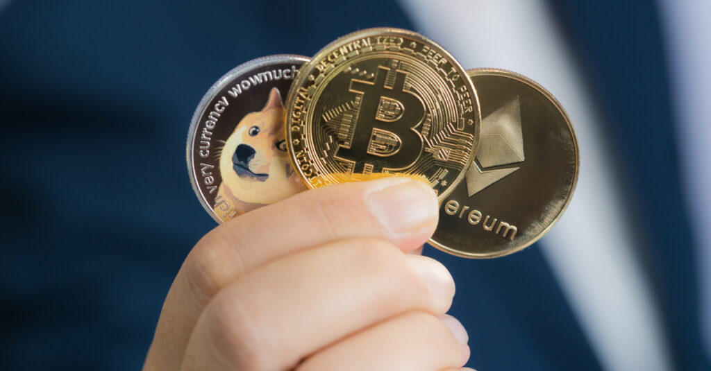 eth btc and doge coins held in fingers