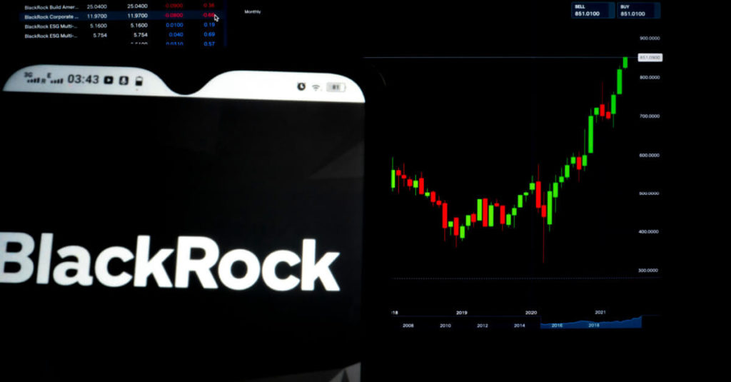 The BlackRock logo shown on a laptop screen sitting in front of a candlestick chart
