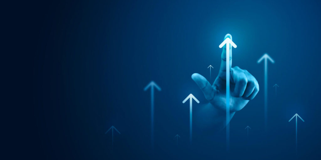 a hand on an arrow pointing upwards amongst other arrows going upwards on a blue background