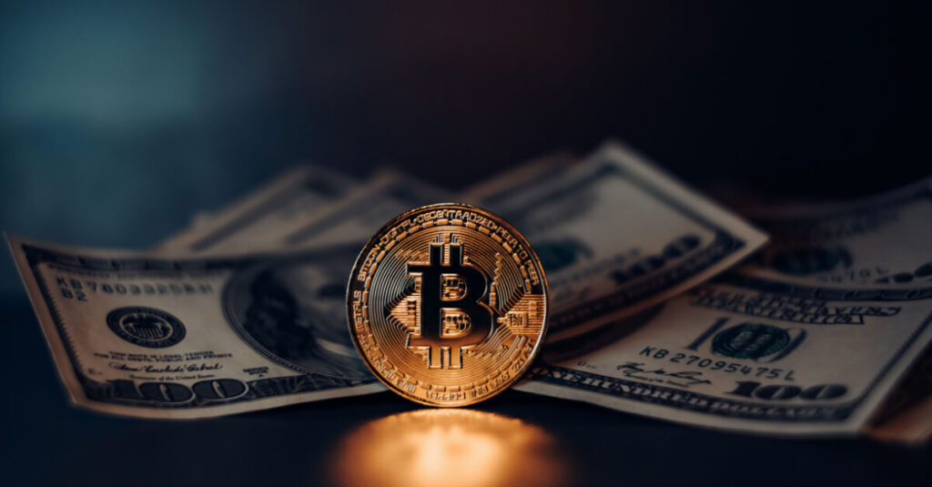 Golden Bitcoin coin sitting in front of dollar bills