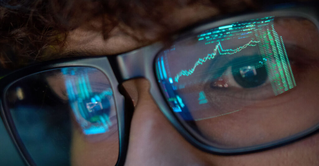 crypto analysts eyes viewed through glasses with reflection of crypto price charts on glasses