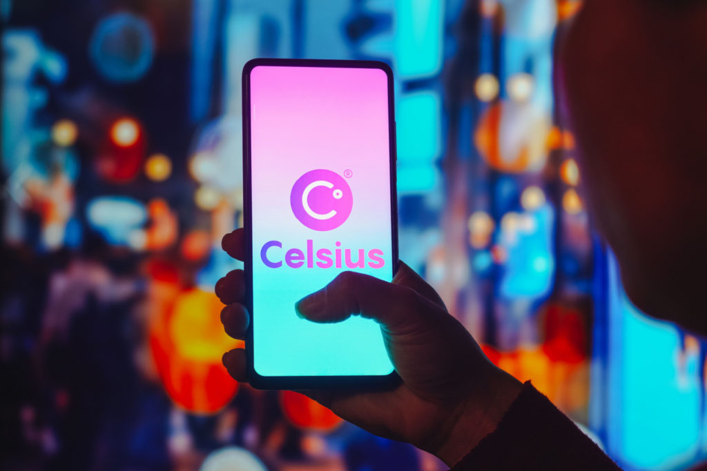 Celsius network’s logo on a movile phone with a man holding his finger to it