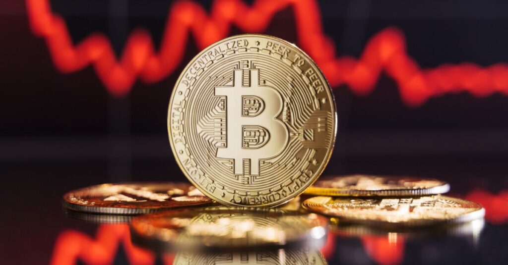 Golden bitcoin with a declining price chart behind
