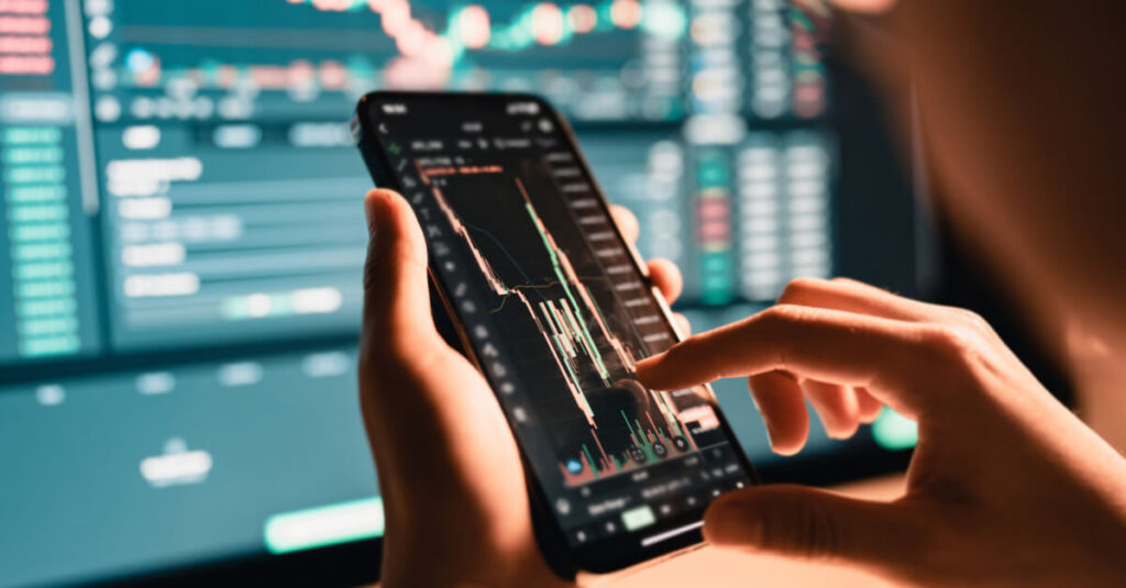 bitcoin trader trades using phone in front of screen