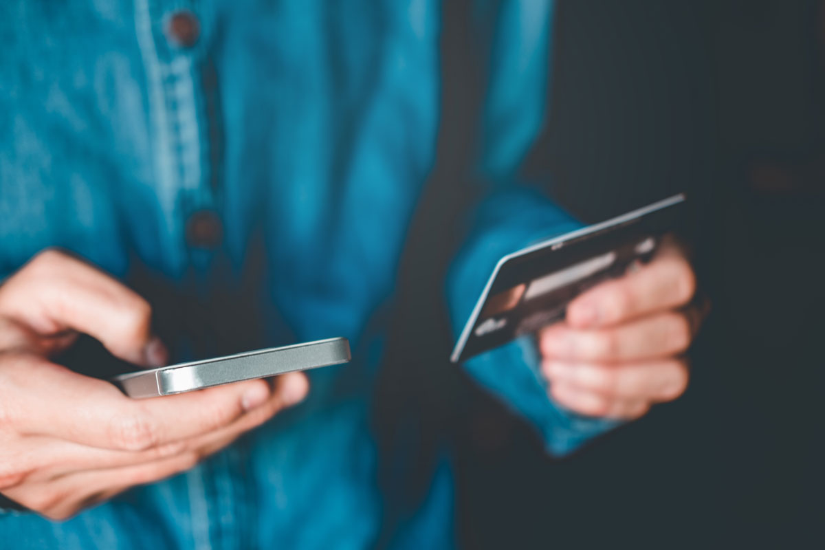 A person buying Bitcoin with a credit card, holding credit card in one hand and phone in the other