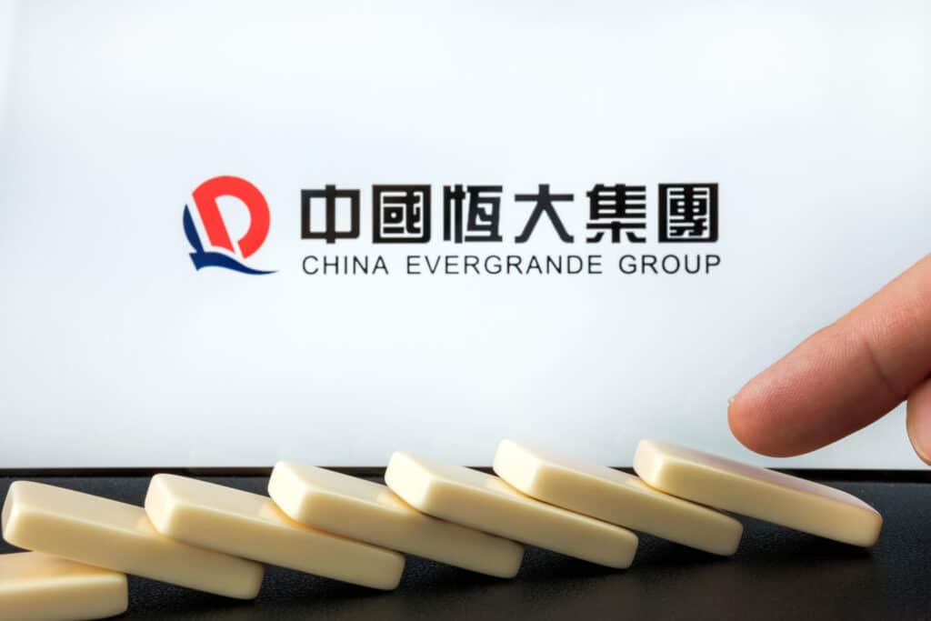 Fichas de dominó cayendo frente al logo de China Evergrande Group.