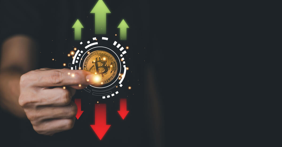 golden bitcoin between fingers with arrows up and down